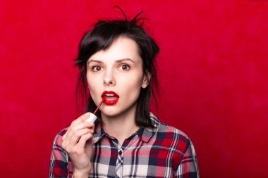 Güzel genç bir kadın rujla dudaklarını boyuyor.