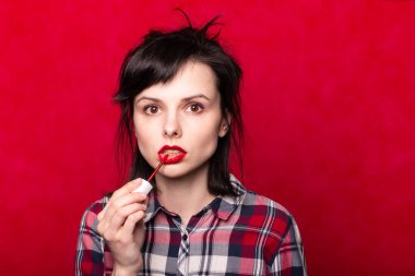 Güzel genç bir kadın rujla dudaklarını boyuyor.