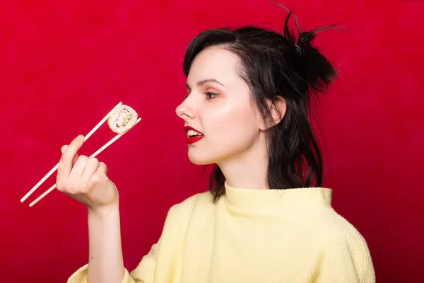 Woman with red lips on a light background eating sushi. asian food