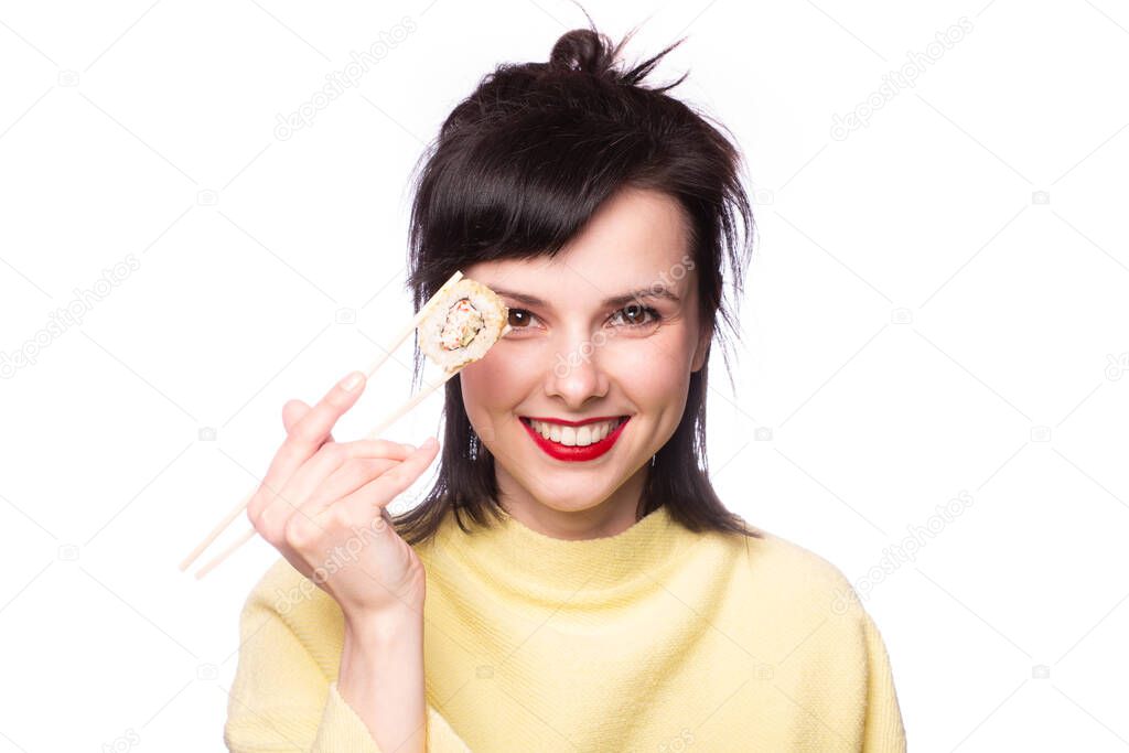 girl with red lipstick on her lips in a yellow sweater holds sticks sushi rolls Japan Asia