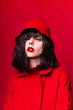 Kırmızı arka planda kırmızı trençkotlu kız.