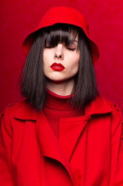 Kırmızı elbiseli, kırmızı arka planda kâküllü bir kadın.