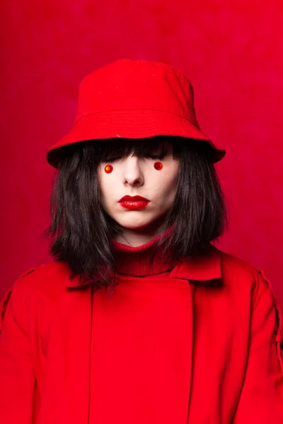 a woman with a bob haircut, wearing a red trench coat