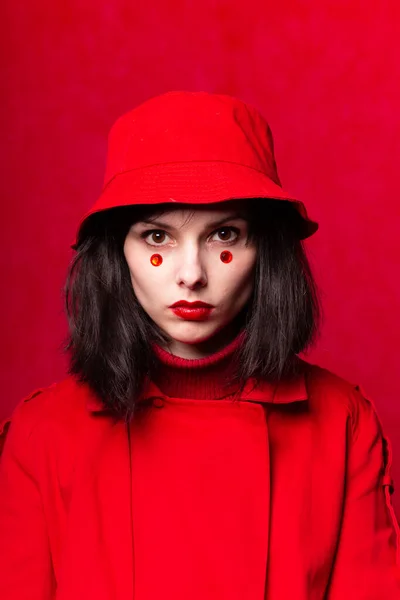 woman in a red coat and panama