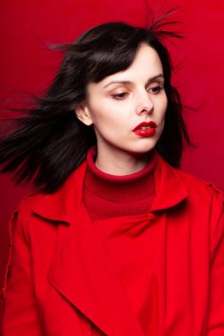 Kırmızılı güzel kadın, saçlarında rüzgar, kırmızı arka plan, beyaz ten