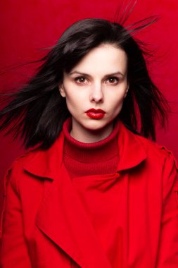 Kırmızılı güzel kadın, saçlarında rüzgar, kırmızı arka plan, beyaz ten