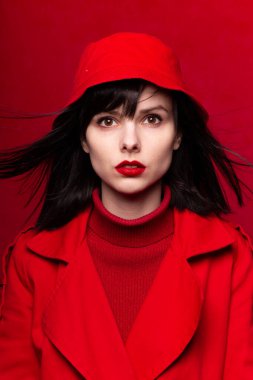 Kırmızı arka planda, uçan saçlı, şık bir kız.