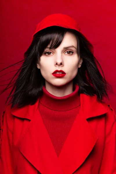 fatal woman in a red cloak, red background, red lipstick, flying hair