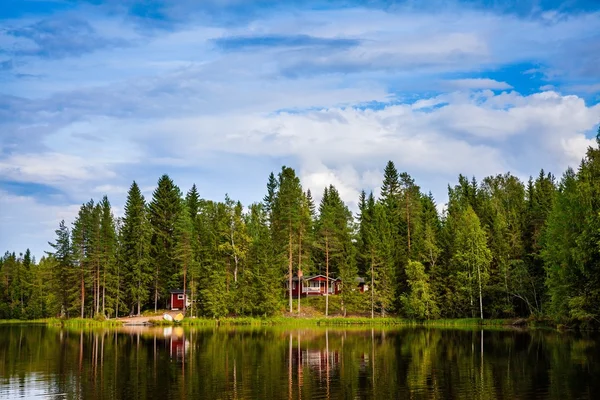 Červená dřevěná chata u jezera — Stock fotografie