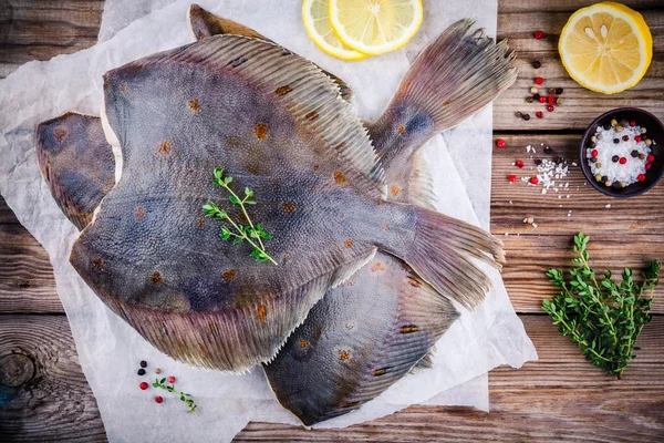 Råa skrubbskädda fisk, plattfisk på träbord — Stockfoto