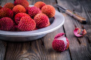 Taze organik lychee meyve bir kase ahşap arka plan üzerinde