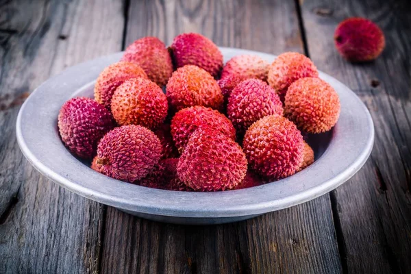 Frische Bio-Litschi-Früchte in einer Schüssel auf Holzgrund — Stockfoto