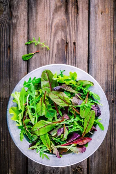 Fresh salad with mixed greens on wooden background — Stock Photo, Image