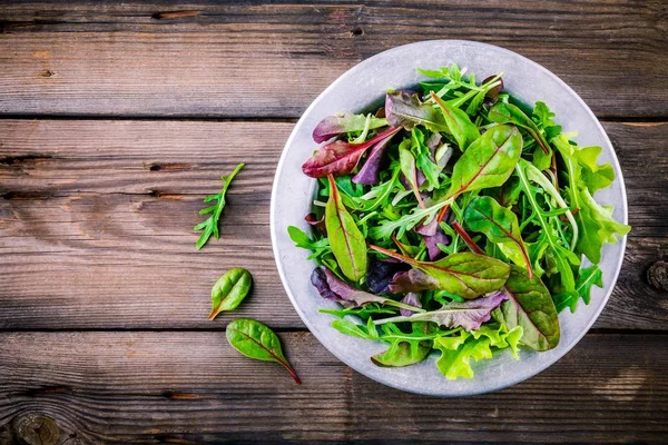 Salada fresca com verduras mistas em fundo de madeira — Fotografia de Stock