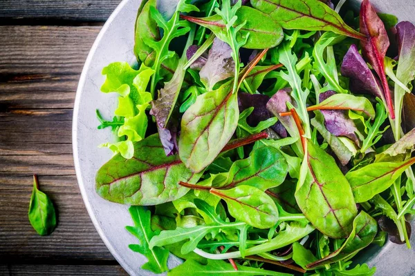 Fresh salad with mixed greens on wooden background closeup — Stock Photo, Image