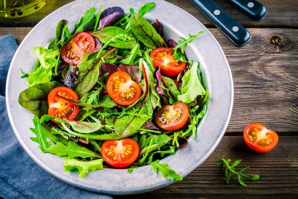 Fresh salad with mixed greens and cherry tomato on wooden background — Stock Photo, Image