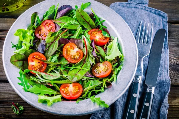 Salada fresca com verduras mistas e tomate cereja em fundo de madeira — Fotografia de Stock