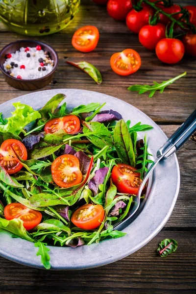 Fresh salad with mixed greens and cherry tomato on wooden background — Stock Photo, Image