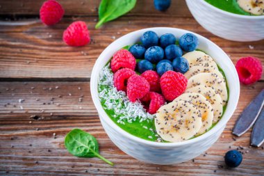 Sağlıklı kahvaltı kase: muz, böğürtlen, ahududu, chia tohum ve Hindistan cevizi ile yeşil ıspanak güler yüzlü