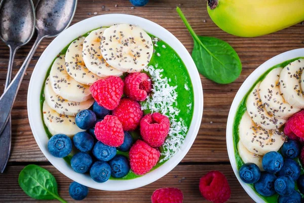 健康的な朝食ボウル: 緑のほうれん草バナナ、ブルーベリー、ラズベリー、チア種子とココナッツのスムージー — ストック写真
