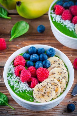 Sağlıklı kahvaltı kase: muz, böğürtlen, ahududu, chia tohum ve Hindistan cevizi ile yeşil ıspanak güler yüzlü