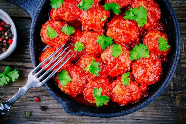 Meatballs with tomato sauce and parsley in cast iron pan — Stock Photo, Image