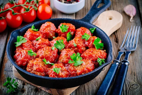 Boulettes de viande avec sauce tomate et persil dans une casserole en fonte — Photo