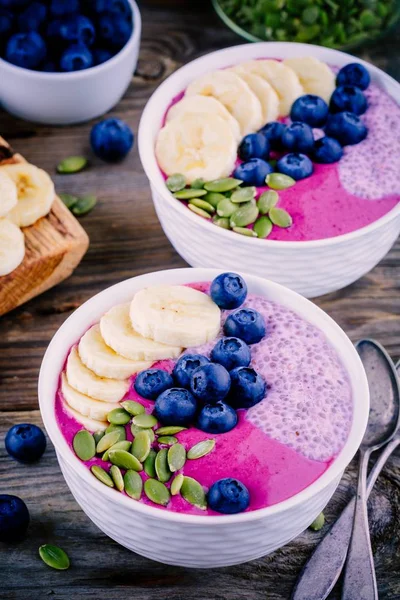 健康的早餐︰ 紫色思慕雪碗与嘉布丁、 香蕉、 新鲜蓝莓和南瓜种子 — 图库照片