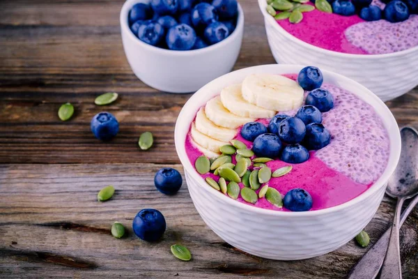 健康的早餐︰ 紫色思慕雪碗与嘉布丁、 香蕉、 新鲜蓝莓和南瓜种子 — 图库照片