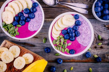 Sağlıklı Kahvaltı: chia puding, muz, taze yaban mersini ve kabak çekirdeği ile mor güler yüzlü kase