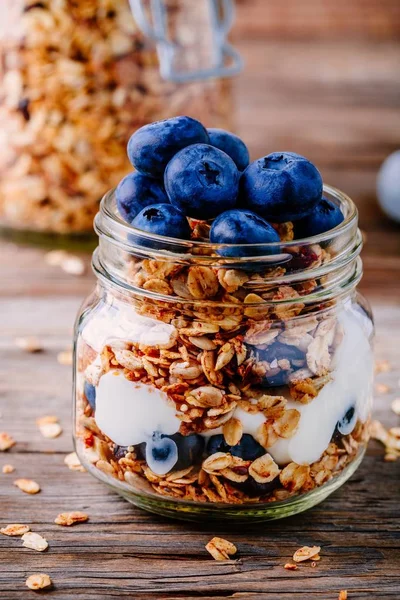 健康早餐吃冻糕与酸奶、 做格兰诺拉麦片和新鲜蓝莓在玻璃罐里 — 图库照片
