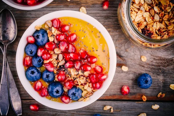 夏日健康早餐芒果冰沙碗麦片、 蓝莓、 石榴和正大种子 — 图库照片