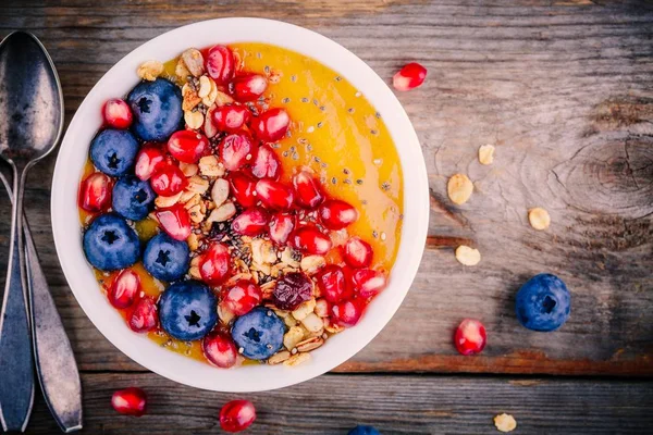 夏日健康早餐芒果冰沙碗麦片、 蓝莓、 石榴和正大种子 — 图库照片