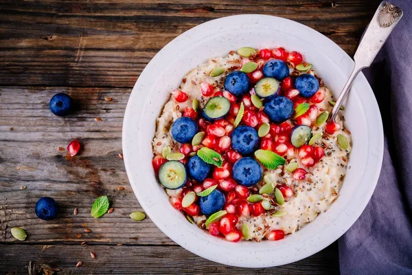 健康早餐碗麦片粥新鲜蓝莓，石榴，薄荷，嘉、 亚麻和南瓜种子 — 图库照片