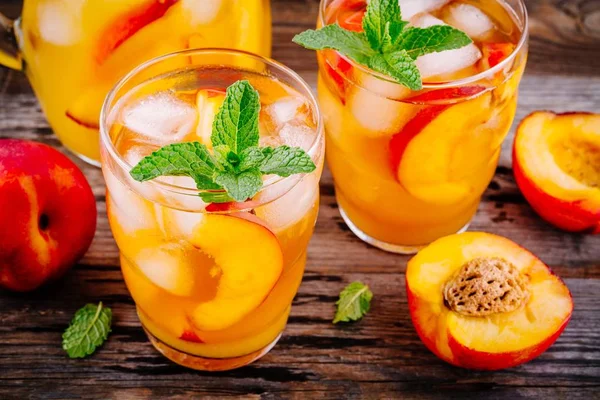 Летние прохладительные напитки: домашняя персиковая сангрия со льдом и мята в стаканах — стоковое фото