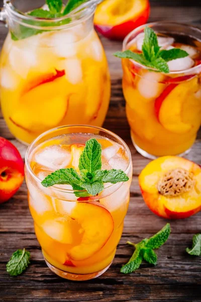 Bebidas frias de verão: chá de gelo de pêssego caseiro com cubos de gelo e hortelã em óculos — Fotografia de Stock