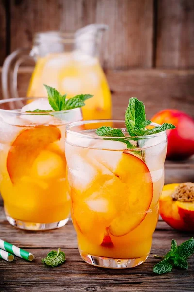 Bebidas frias de verão: chá de gelo de pêssego caseiro com cubos de gelo e hortelã em óculos — Fotografia de Stock