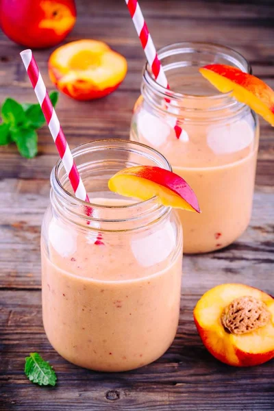 Smoothies pêssego saudável em um frasco de pedreiro com hortelã em fundo de madeira — Fotografia de Stock