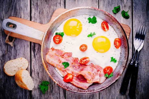 Завтрак с яичницей, беконом, помидорами и петрушкой — стоковое фото