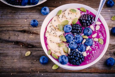 Taze böğürtlen, yaban mersini, muz, ayçiçeği çekirdeği, kabak çekirdeği, chia tohum ve Hindistan cevizi ile güler yüzlü kase