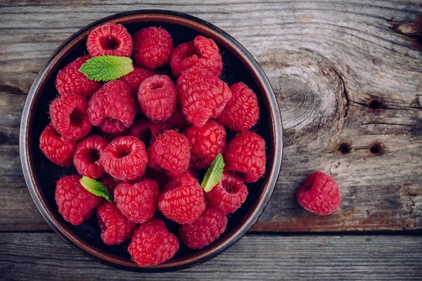 Fresh ripe organic raspberry in a plate on a wooden background — Stock Photo, Image