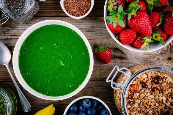 Tazón de batidos verdes. espinacas, plátanos, fresas, arándanos, granola y semillas — Foto de Stock