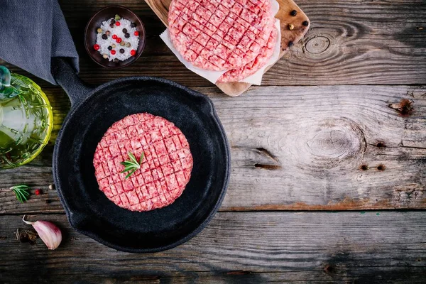 Carne moída crua costeletas de bife de hambúrguer Em uma frigideira de ferro fundido — Fotografia de Stock