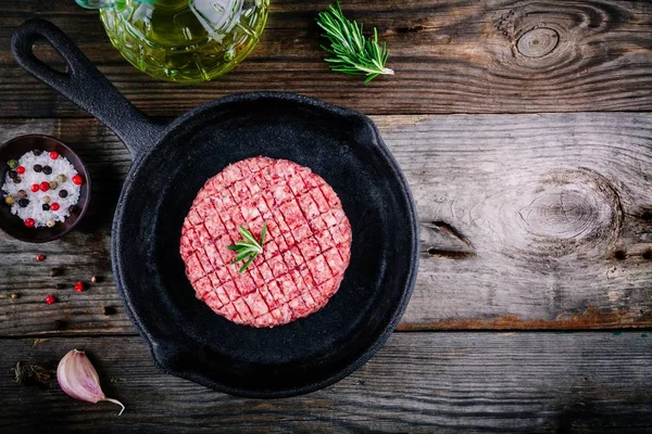 Carne moída crua costeletas de bife de hambúrguer Em uma frigideira de ferro fundido — Fotografia de Stock