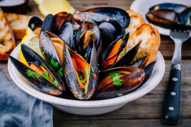 Sos ve maydanozlu lezzetli deniz ürünleri midyeleri. Limon ve baget. Deniz kabuklarında istiridye.  