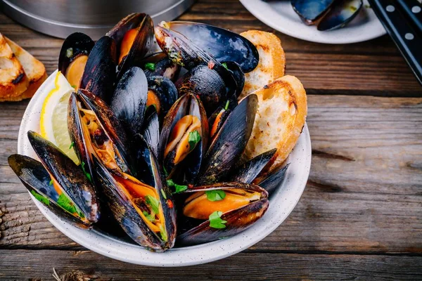 Köstliche Meeresfrüchte-Muscheln mit Sauce und Petersilie. Zitrone und Baguette. Muscheln in den Schalen. — Stockfoto