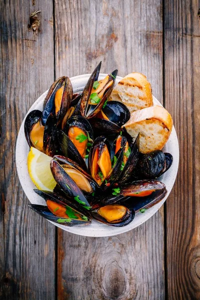 Sos ve maydanozlu lezzetli deniz ürünleri midyeleri. Limon ve baget. Deniz kabuklarında istiridye.  