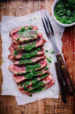 Sliced grilled barbecue beef steak with green chimichurri sauce clipart