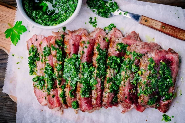 Sliced grilled barbecue beef steak with green chimichurri sauce — Stock Photo, Image