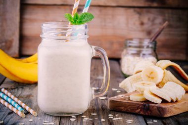 muz smoothie ahşap arka plan üzerinde mason kavanoza yulaf gevreği ile